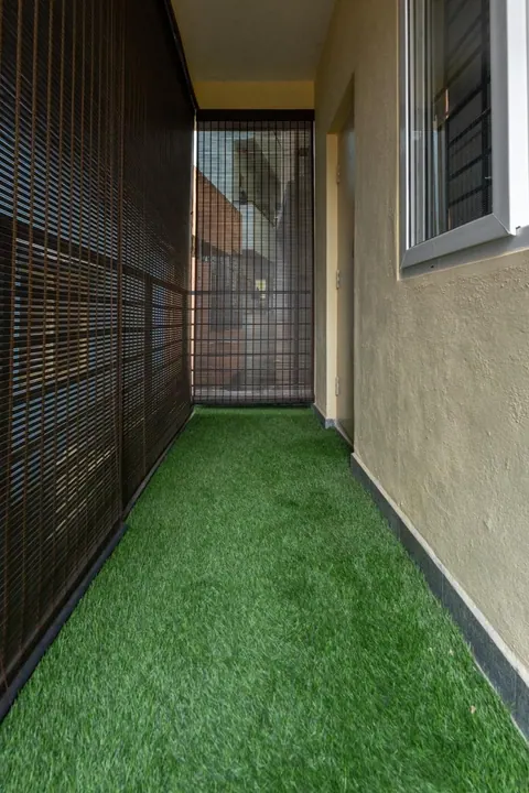 Balcony design with artificial turf flooring and bamboo chick blinds