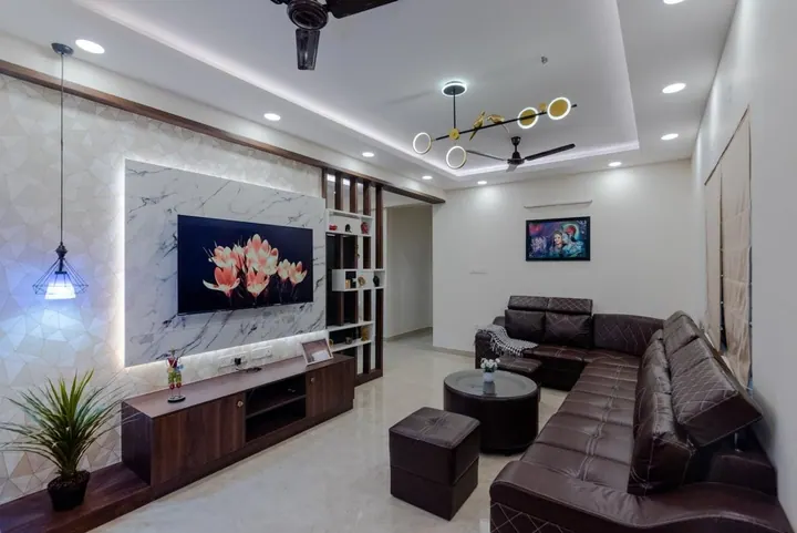 Living room with a backlit marble TV panel, jaali partition and recessed lighting